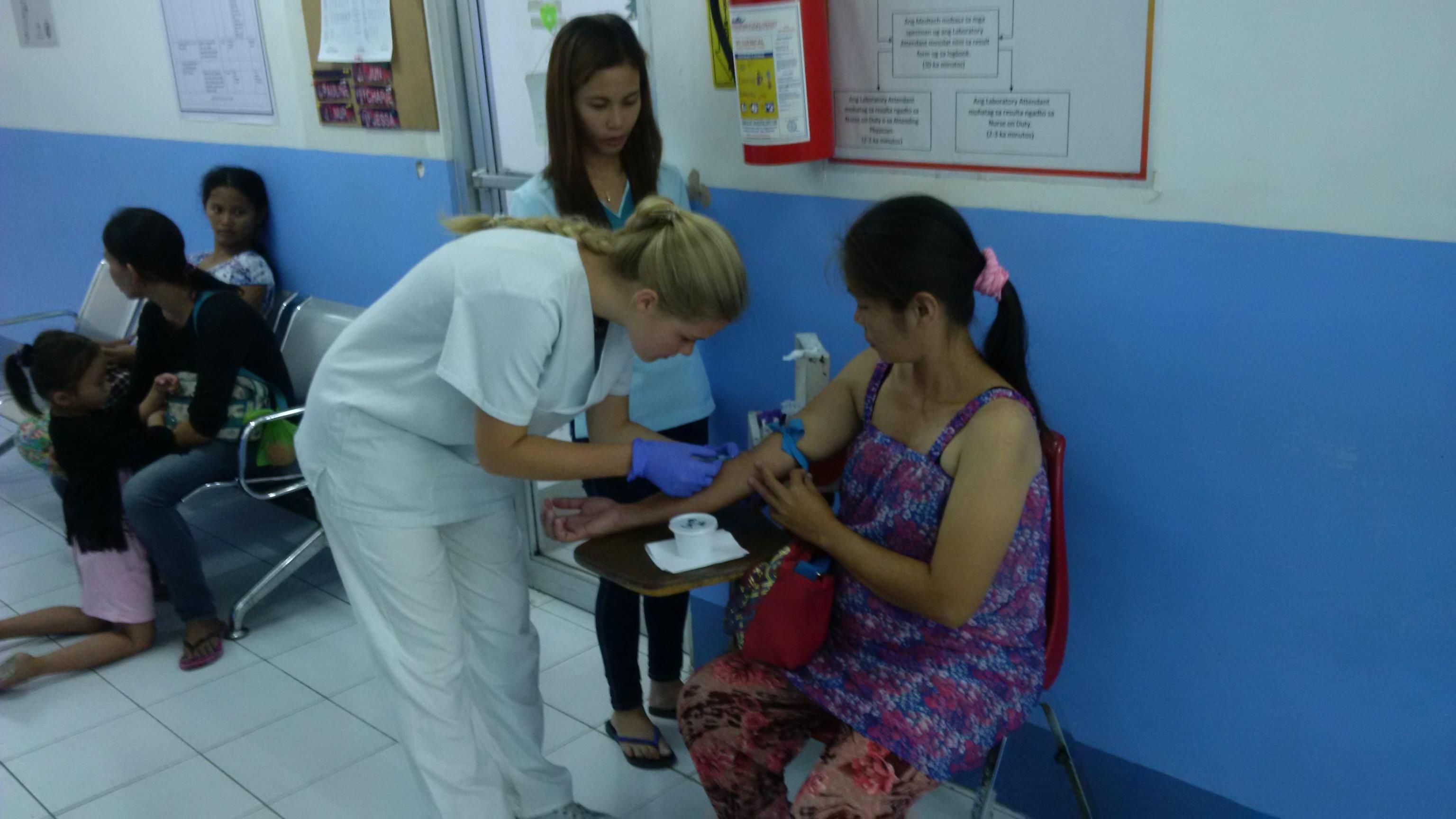 Interna de medicina en Filipinas sacando sangre de una paciente junto a una doctora local. Una doctora y una interna de medicina durante un chequeo a una paciente en Filipinas.
